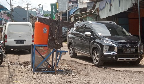 Warga Wangkal Pasang Tandon Air di Tengah Jalan Rusak